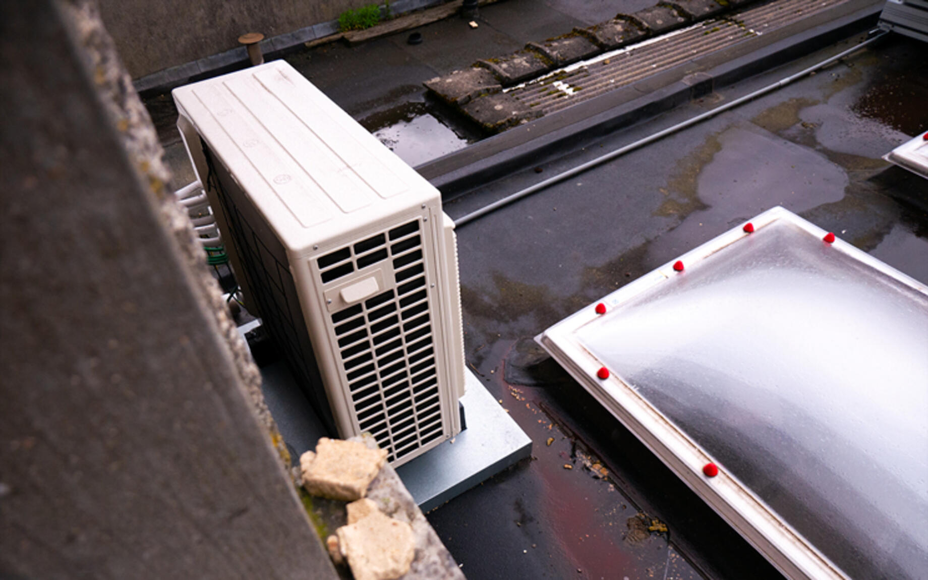 Buitenunit van een warmtepomp op een plat dak
