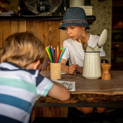 Twee jongens aan een eettafel die druk aan het kleuren zijn