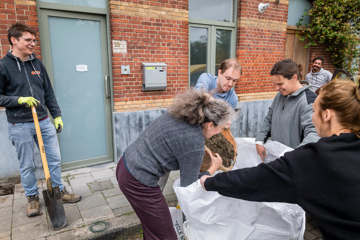 Buren ontharden voetpad en verzamelen puin in puinzak