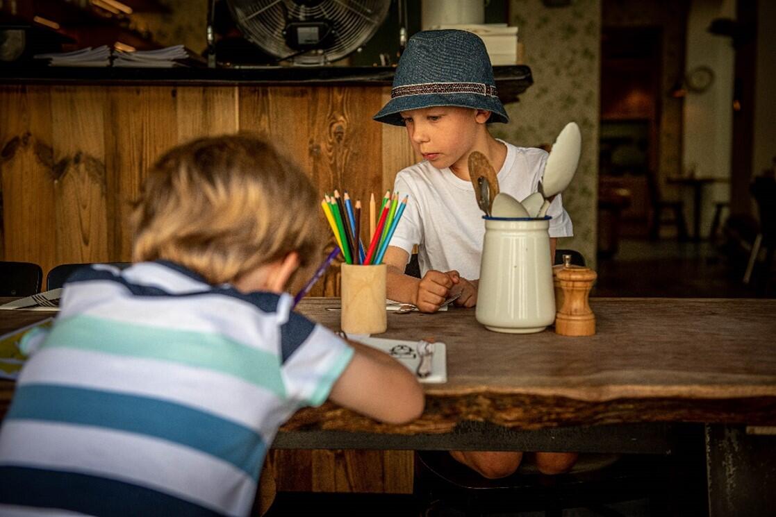 Twee jongens aan een eettafel die druk aan het kleuren zijn